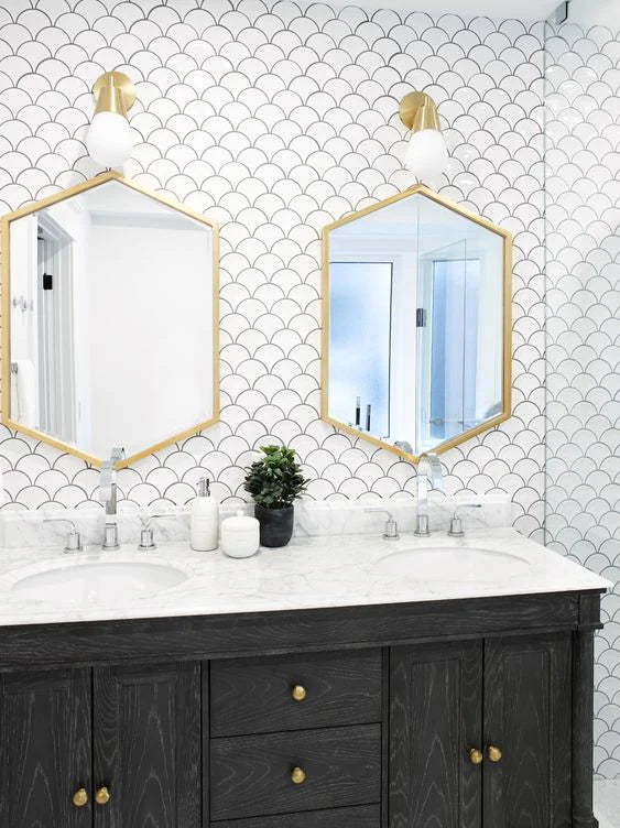PGFS-3051 White Gloss Glazed Porcelain Fishscale 95x87mm tiles covering a bathroom feature wall behind a dark double vanity with gold hexagonal mirrors and brass sconce lighting.