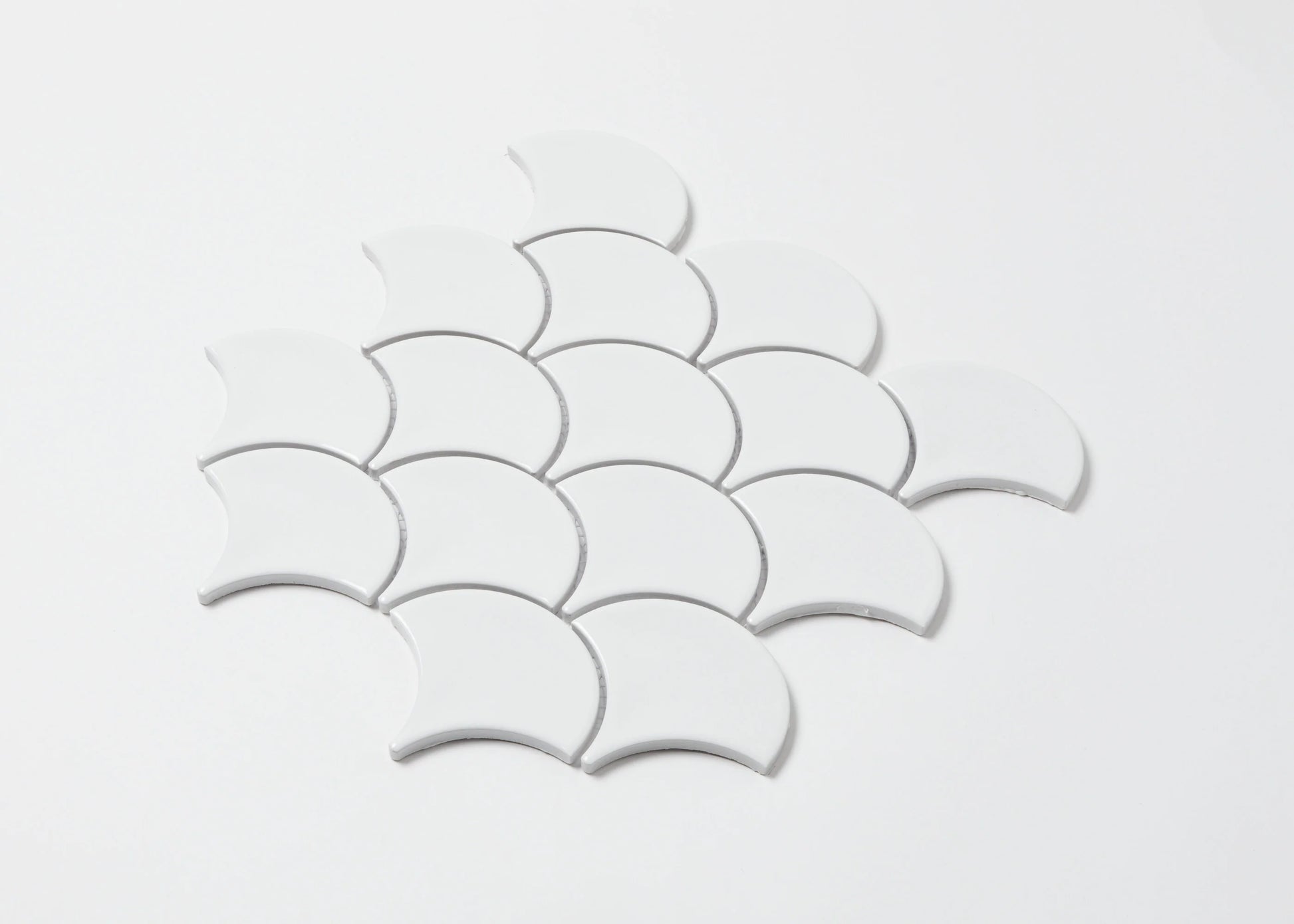 Pack shot of PGFS-3051 White Gloss Glazed Porcelain Fishscale 95x87mm tiles arranged in an overlapping scallop pattern against a white background.