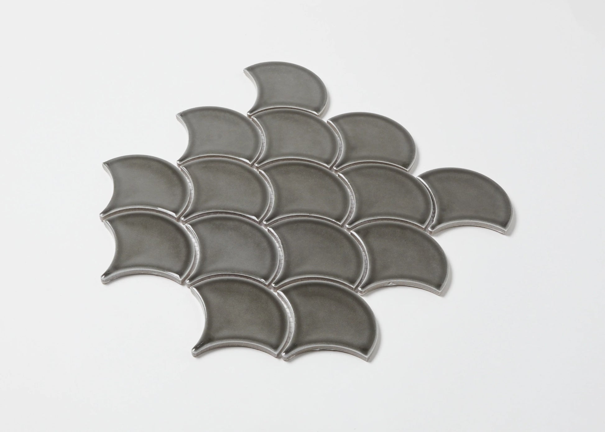 Pack shot of PGFS-8874 Charcoal Gloss Glazed Porcelain Fishscale 95x87mm tiles arranged in an overlapping fish scale pattern with a glossy grey finish.