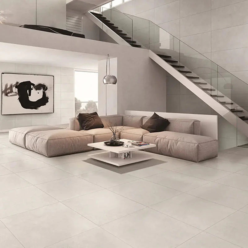 Plazzo Silver Matt Rectified 300x300mm tiles covering a spacious modern living room floor with a sectional sofa, glass staircase, and pendant light.