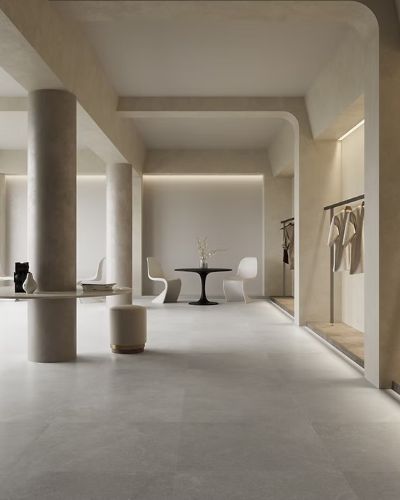 Provence Ash Lapatto Rectified 600x600mm floor tiles installed in a minimalist retail interior featuring cylindrical columns, arched ceilings, and a black tulip table.
