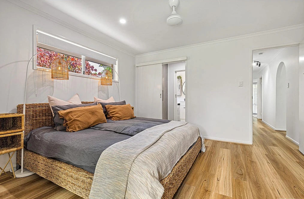Queensland Spotted Gum Elegant SPC Hybrid 6.5mm Flooring 5+1.5mm installed in a bright master bedroom with wicker bed frame, pendant lights, and ensuite access.