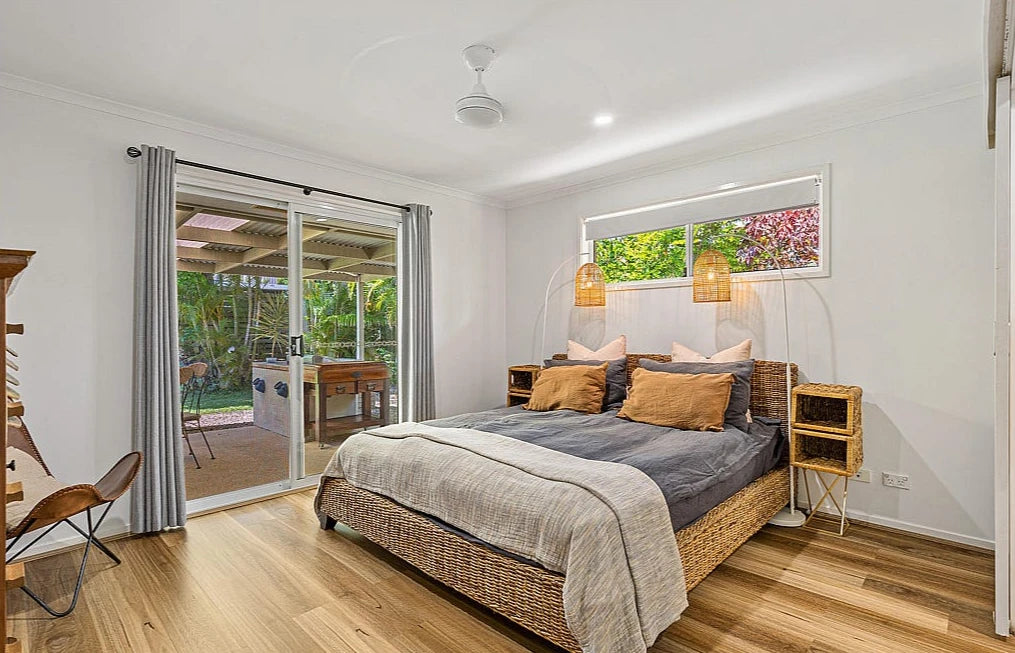 Queensland Spotted Gum Elegant SPC Hybrid 6.5mm Flooring 5+1.5mm installed in a bright bedroom with wicker bed, pendant lights, and sliding door to outdoor patio.