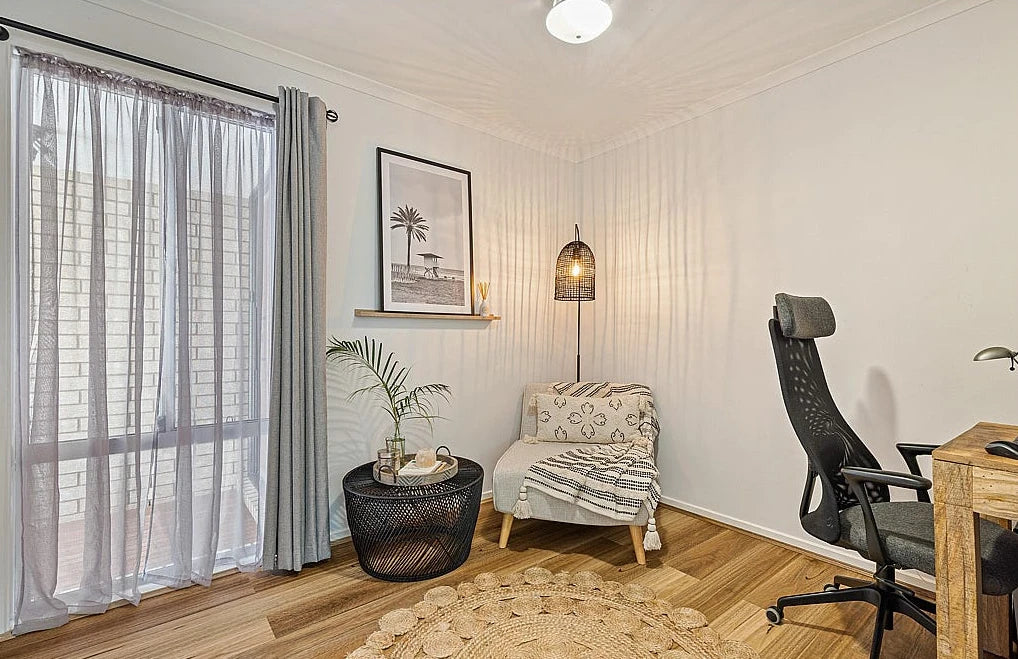 Queensland Spotted Gum Elegant SPC Hybrid 6.5mm Flooring 5+1.5mm installed in a cosy home office and lounge area featuring a cushioned armchair, rattan pendant lamp, and sliding glass door.