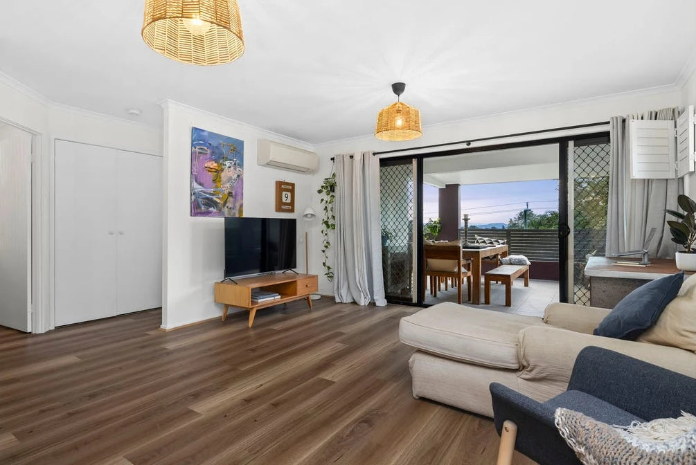 Queensland Spotted Gum Elegant SPC Hybrid 6.5mm Flooring 5+1.5mm installed in a bright living room with rattan pendant lights and sliding balcony doors.
