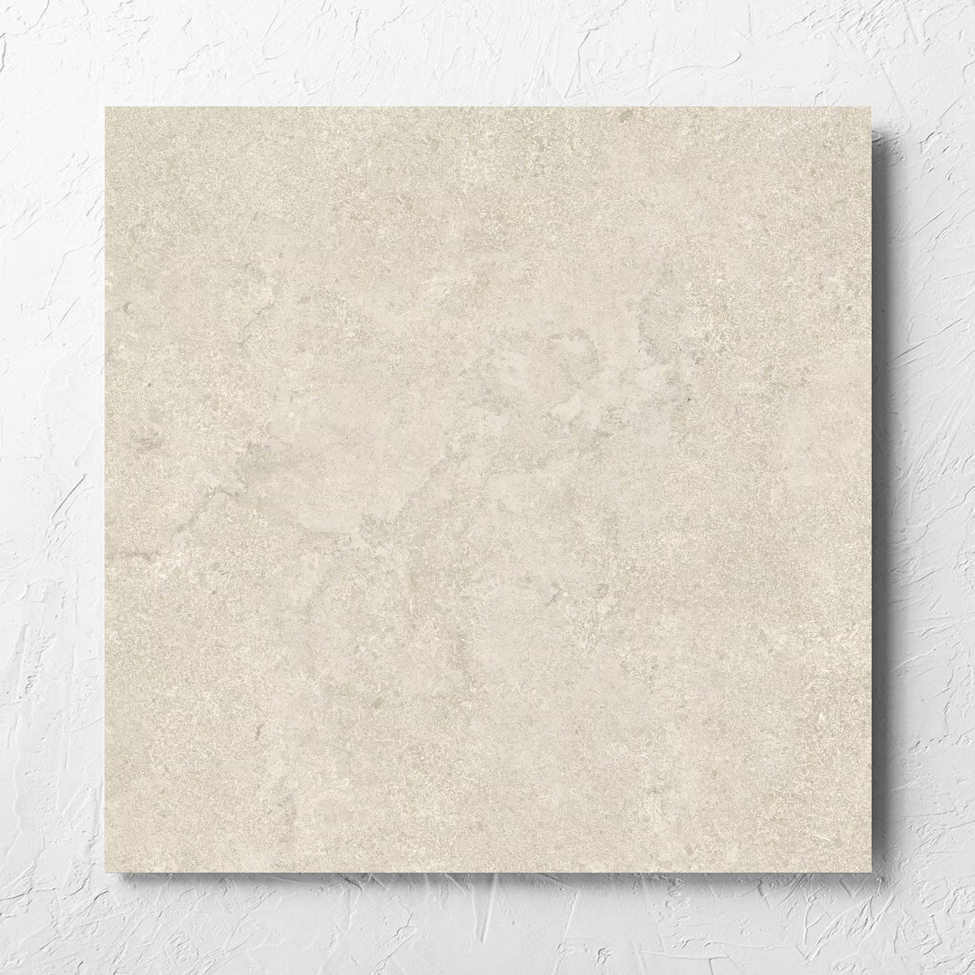 Roman Travertine Beige 600x600mm tile laid flat on a white rendered wall, showing the beige matt surface