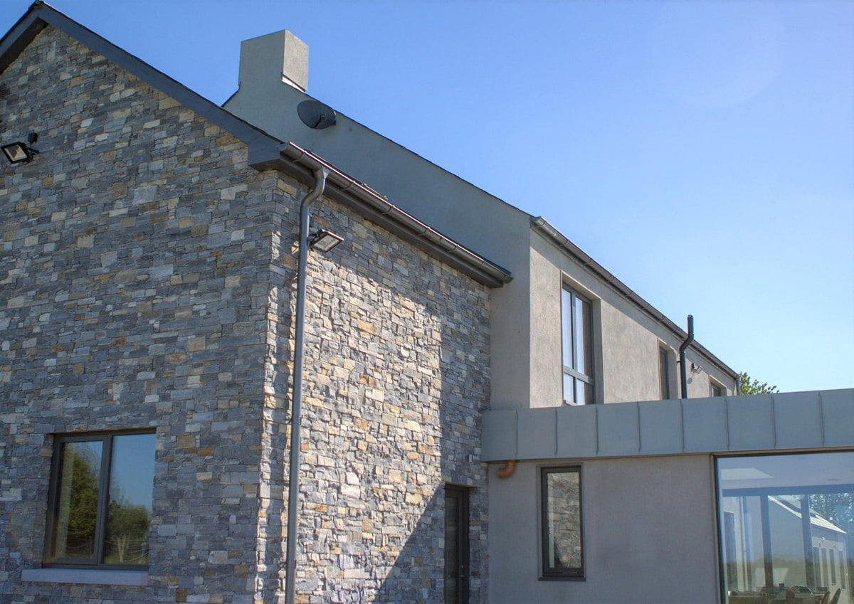Sapphire Mica Schist Z Panel Interlock 200x600mm installed on a contemporary home exterior facade, showcasing natural grey and gold toned stone cladding with a render extension and glass conservatory.
