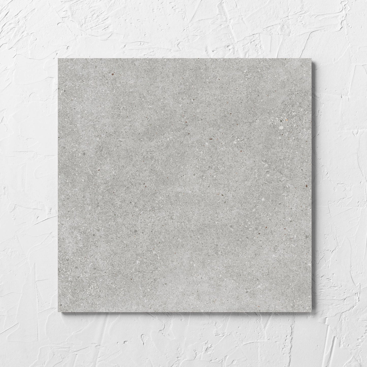 Serenity Concrete Grey 300x300mm tile laid flat on a white rendered wall, showing the matt surface