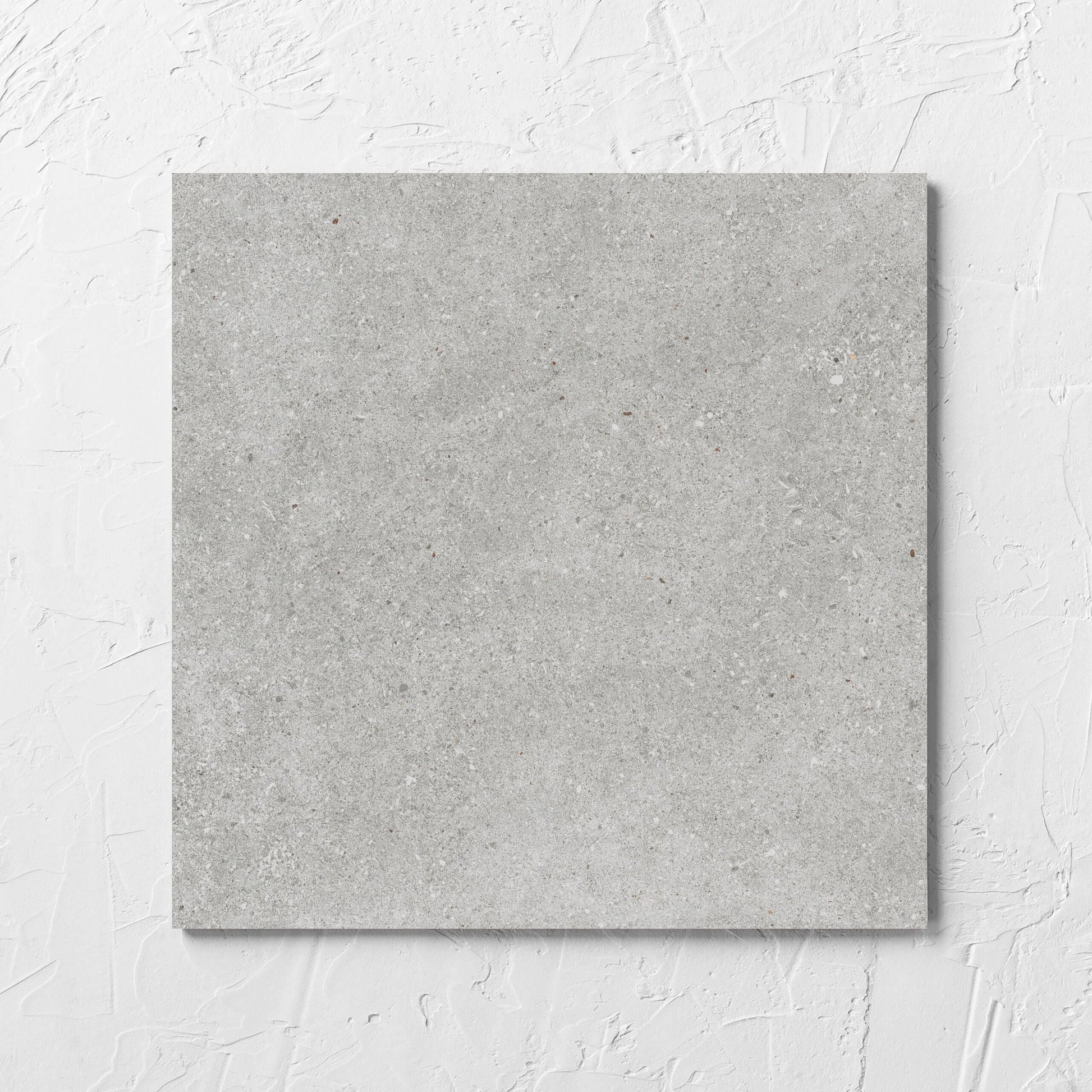 Serenity Concrete Grey 300x300mm tile laid flat on a white rendered wall, showing the matt surface