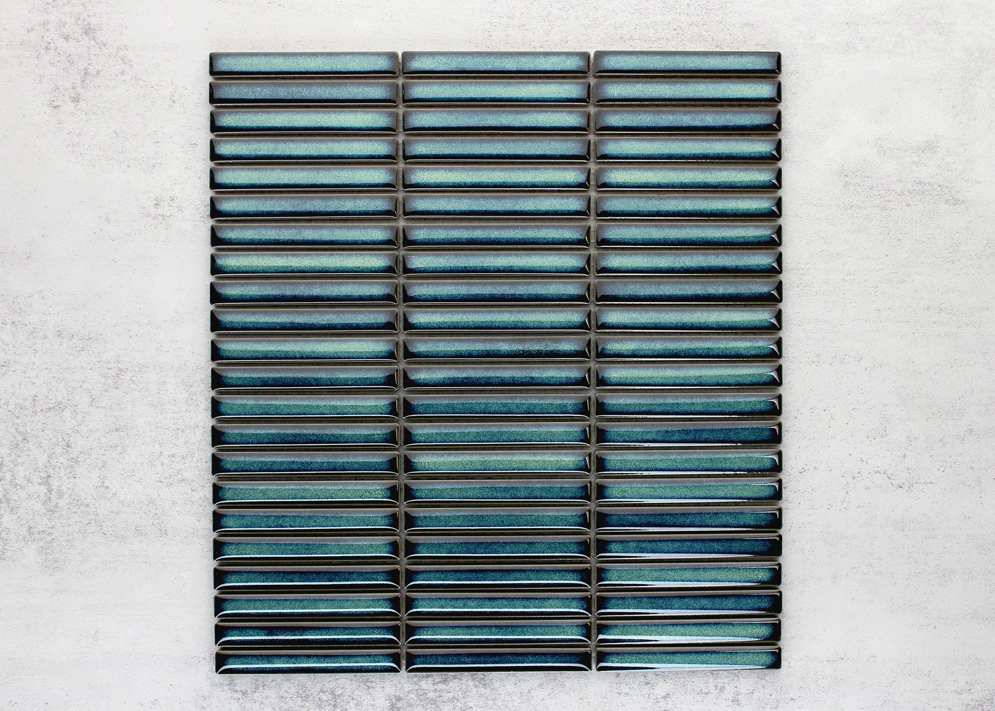 Flat lay pack shot of Shadow Dark Green Gloss Porcelain KitKat 12x92mm mosaic sheet showing elongated glossy teal-green finger tiles arranged in stacked rows.