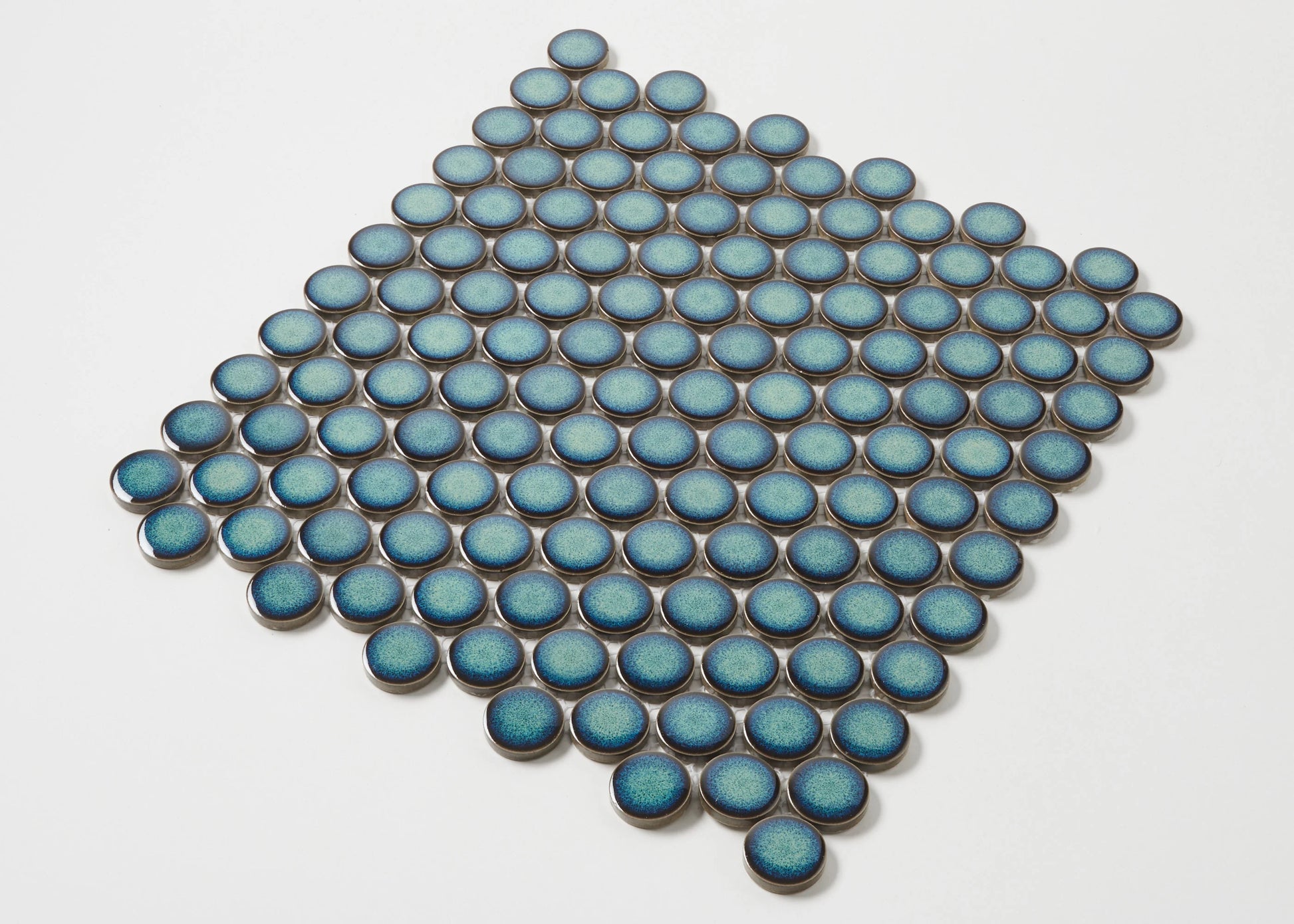 Pack shot of Shadow Green Gloss Glazed Porcelain Penny Round 28mm Diameter tiles arranged in a diamond pattern, showcasing their teal blue gloss finish and circular shape.