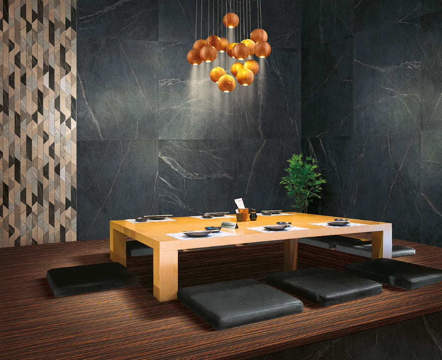 Soap Stone Black Natural 600x1200mm tiles cladding the walls of a moody Japanese restaurant dining room with a low table and globe pendant lights.