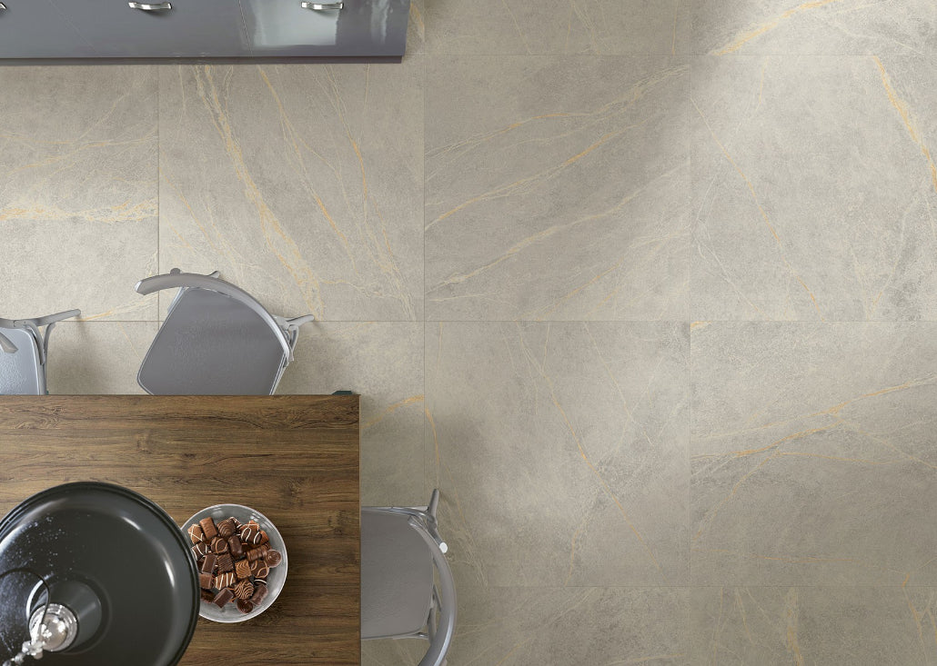 Soap Stone White External 600x600mm tiles installed on a dining room floor viewed from above with a wooden table, grey chairs, and a bowl of chocolates.