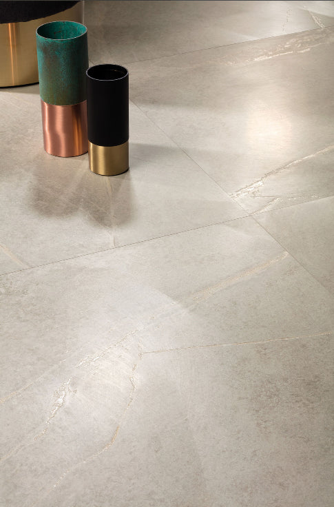 Soap Stone White External 600x600mm tiles installed as a large-format polished floor with subtle veining, styled with metallic decorative cylinders.