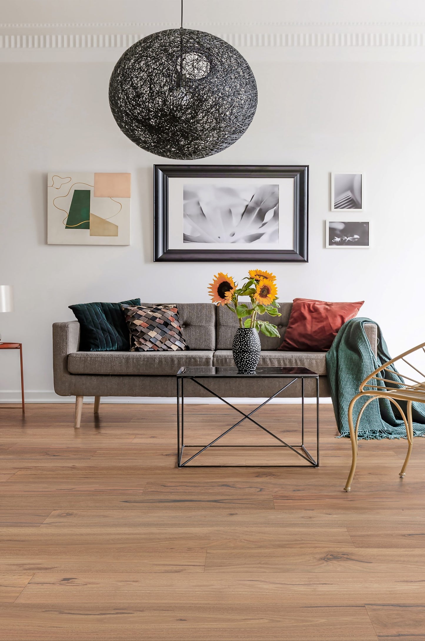 Spotted Gum Rustic Grade Engineered Australian Classic Flooring 14/3mm installed in a modern living room with a grey sofa, black wire pendant light, and sunflowers.