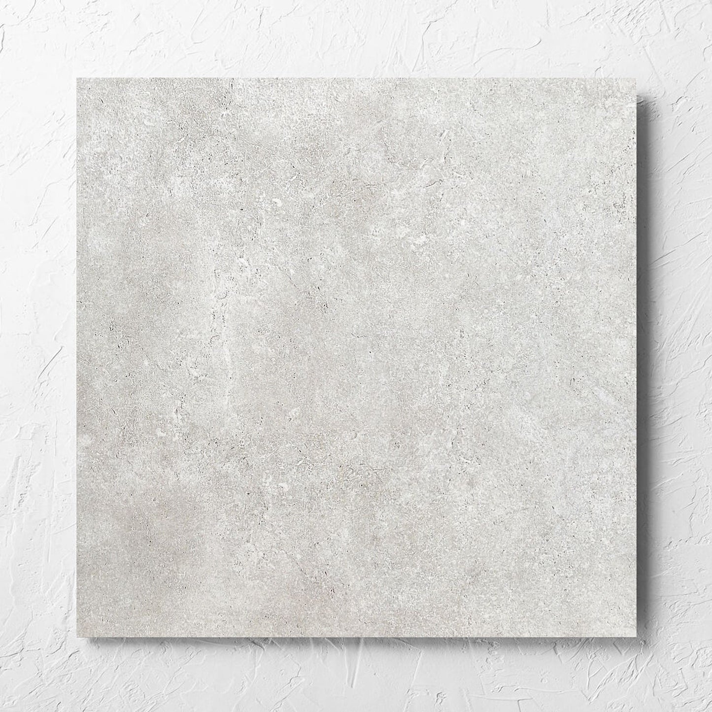 Stella Ash Matt 600x600mm tile laid flat on a white rendered wall, showing the tile surface