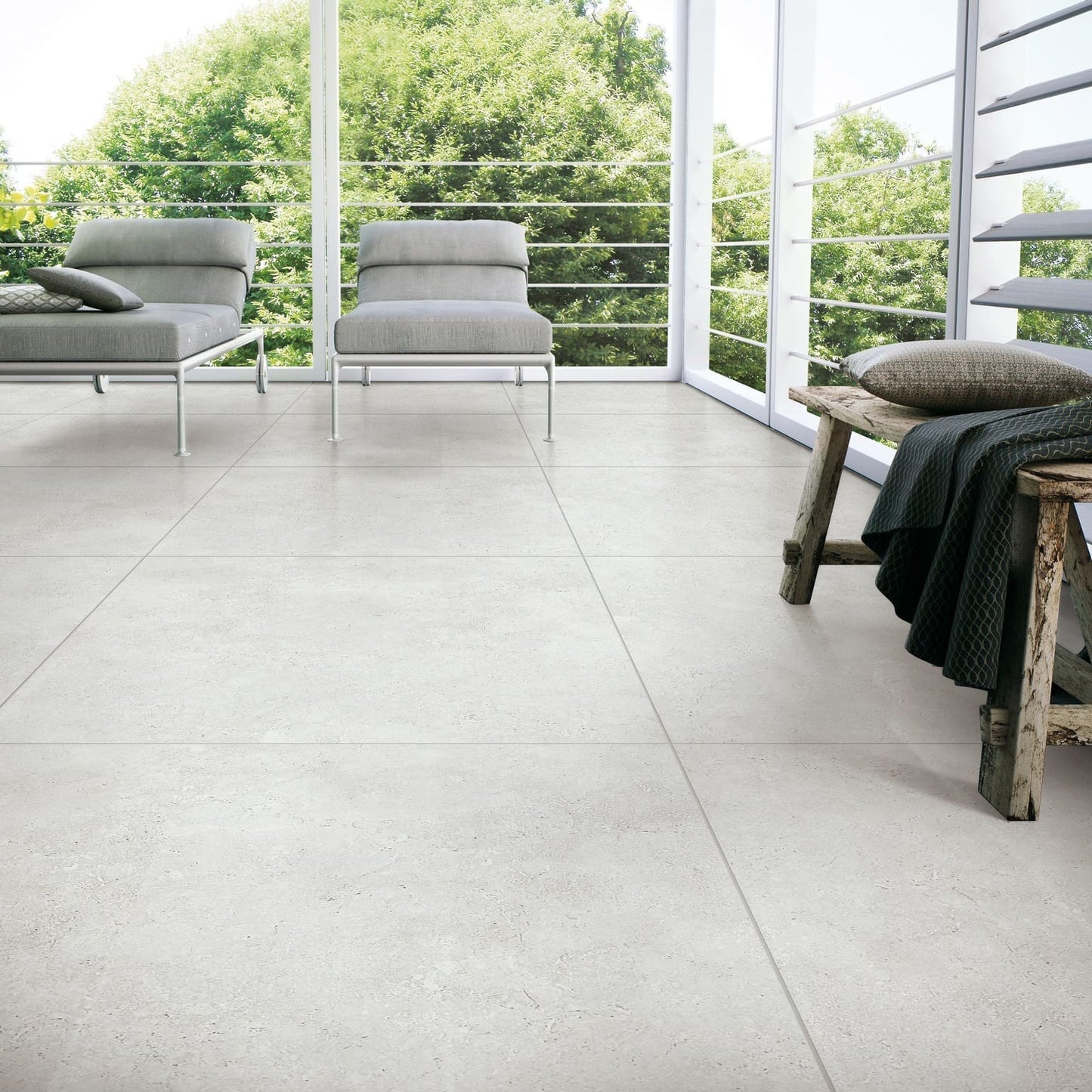 Stella Ash Matt 600x600mm porcelain tiles installed in a bright open-plan living space with modern lounge chairs and floor-to-ceiling windows.