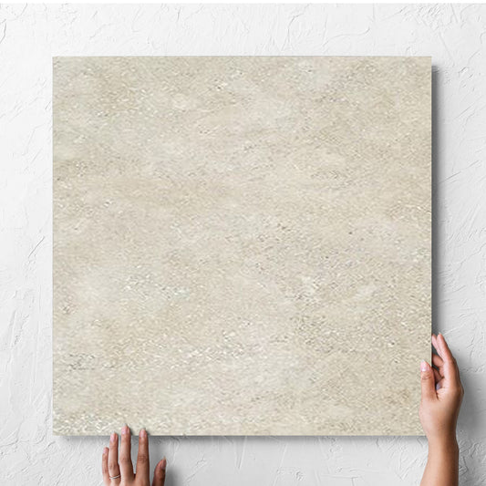 Hand holding a single Stella Beige Lappato 600x600mm tile against a white rendered wall, showing the beige lappato surface