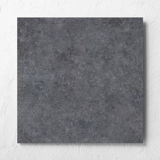 Stella Charcoal Lappato 600x600mm tile laid flat on a white rendered wall, showing the lappato surface