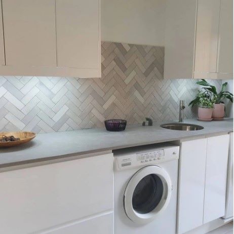 T-Brick Seashell Gloss Subway 52x160mm tiles installed in a herringbone pattern splashback in a modern laundry room with white cabinetry and round sink.