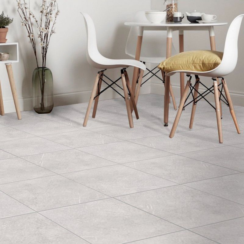 T-Stone White 450x450mm floor tiles installed in a bright dining area with modern white Eames-style chairs and a round white table.