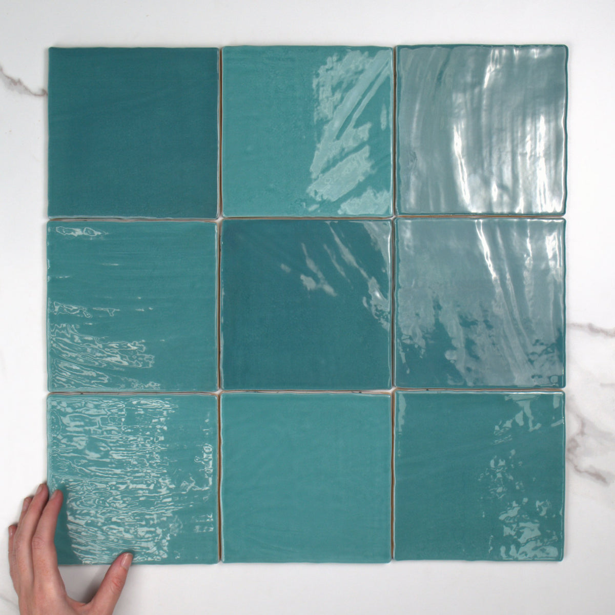Tabarca Turquesa Gloss 150x150mm top view, hand for scale
