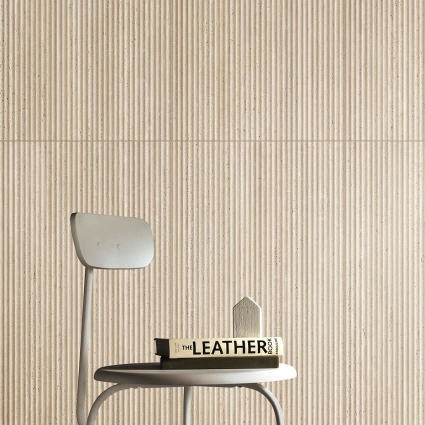 Tallow Bamboo Feature Travertine Look Beige 600x1200mm fluted tiles on a feature wall behind a chair and stacked books