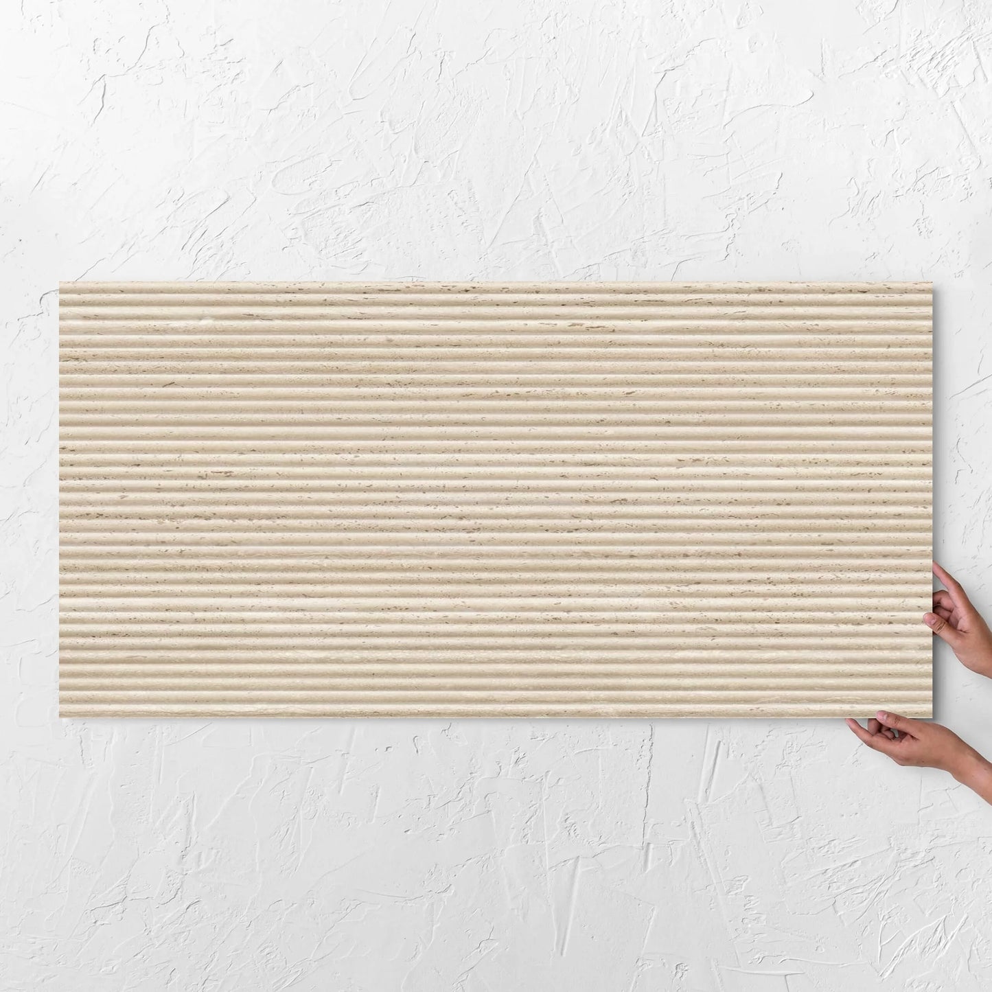 Hands holding a Tallow Bamboo Feature Travertine Look Beige 600x1200mm tile against a white rendered wall, showing the beige textured surface
