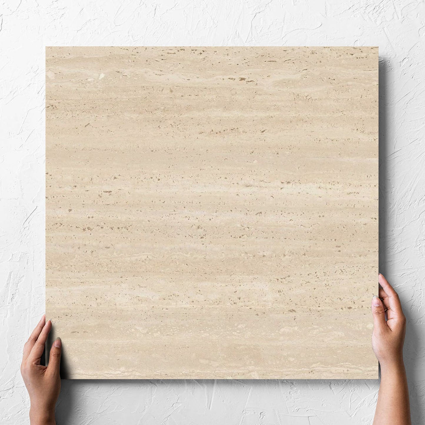 Hand holding a single Tallow Vein Cut Travertine Look Beige 600x600mm tile against a white rendered wall, showing the beige matt surface
