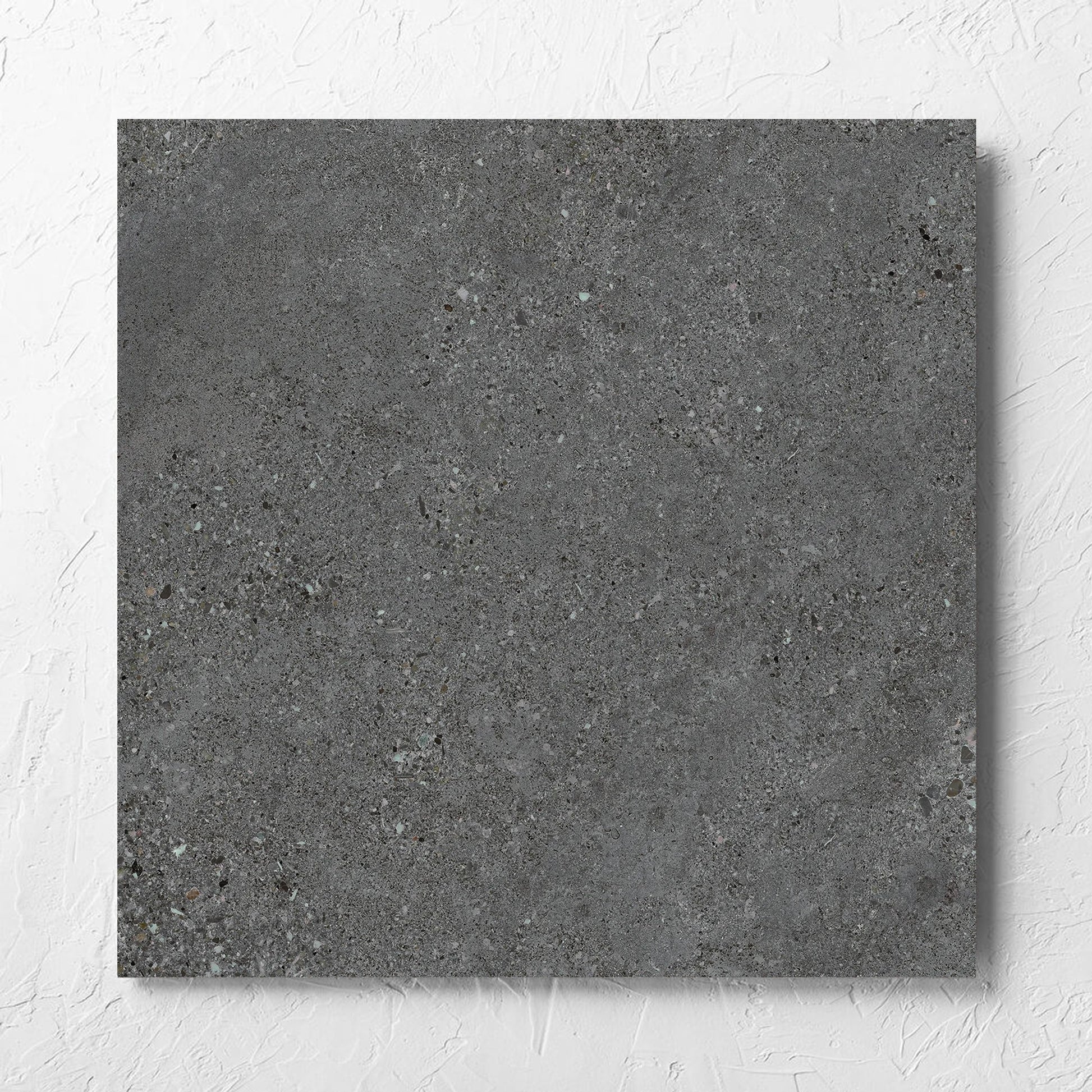 Terramix Charcoal Grip 600x600mm tile laid flat on a white rendered wall, showing the matt surface