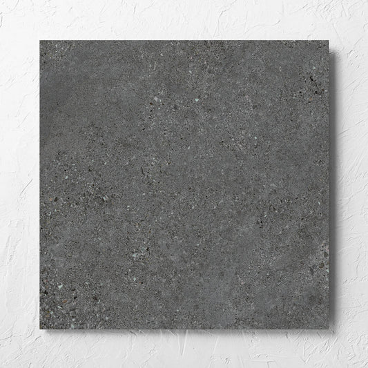 Terramix Charcoal Grip 600x600mm tile laid flat on a white rendered wall, showing the matt surface