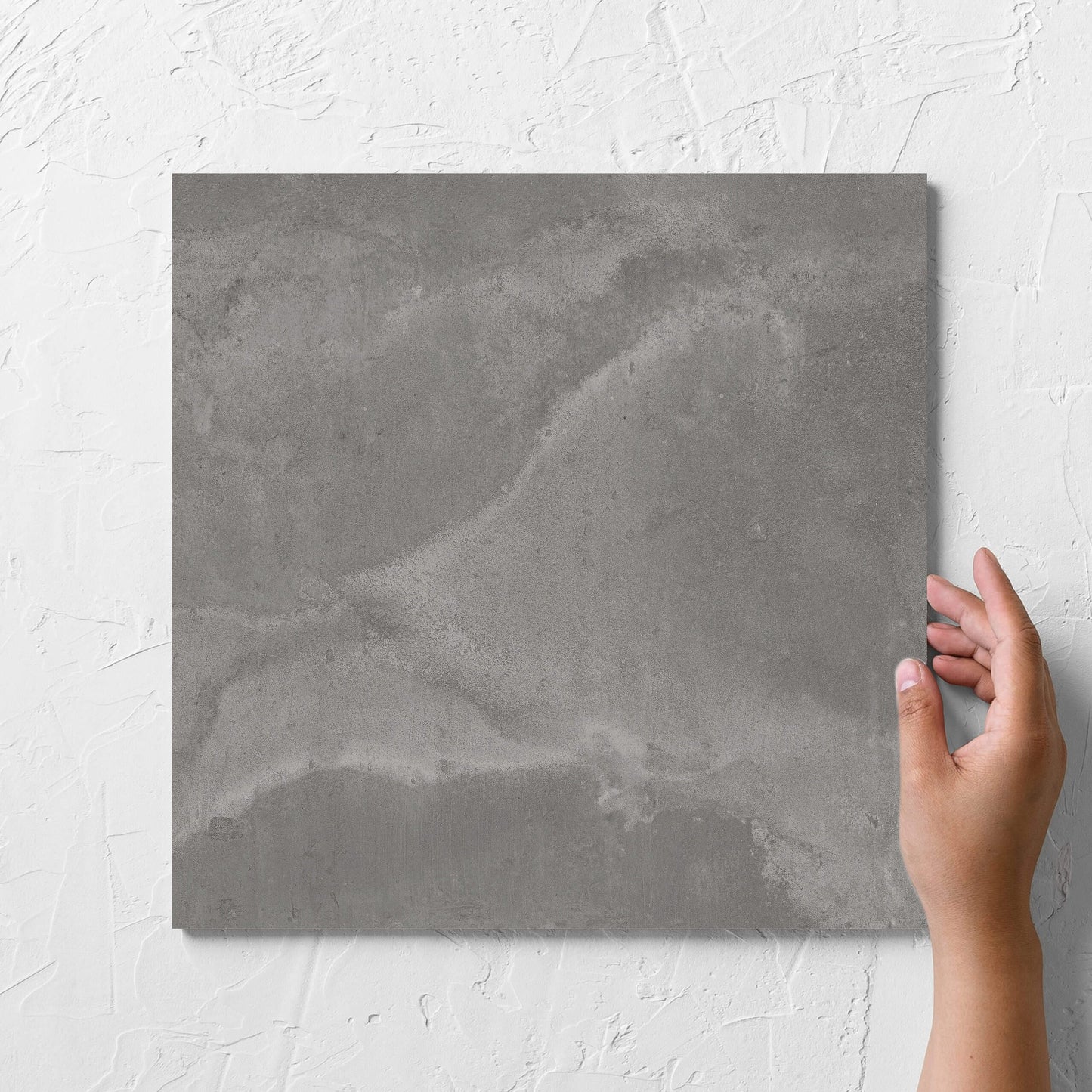Hand holding a single Thor Grey Matt 300x300mm tile against a white rendered wall, showing the matt surface