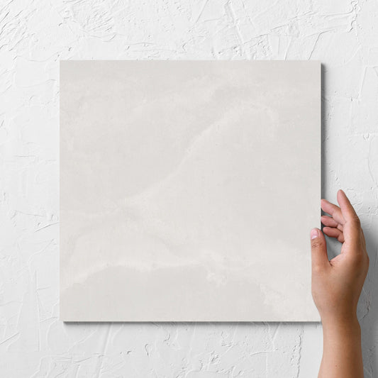 Hand holding a single Thor White Matt 300x300mm tile against a white rendered wall, showing the matt surface