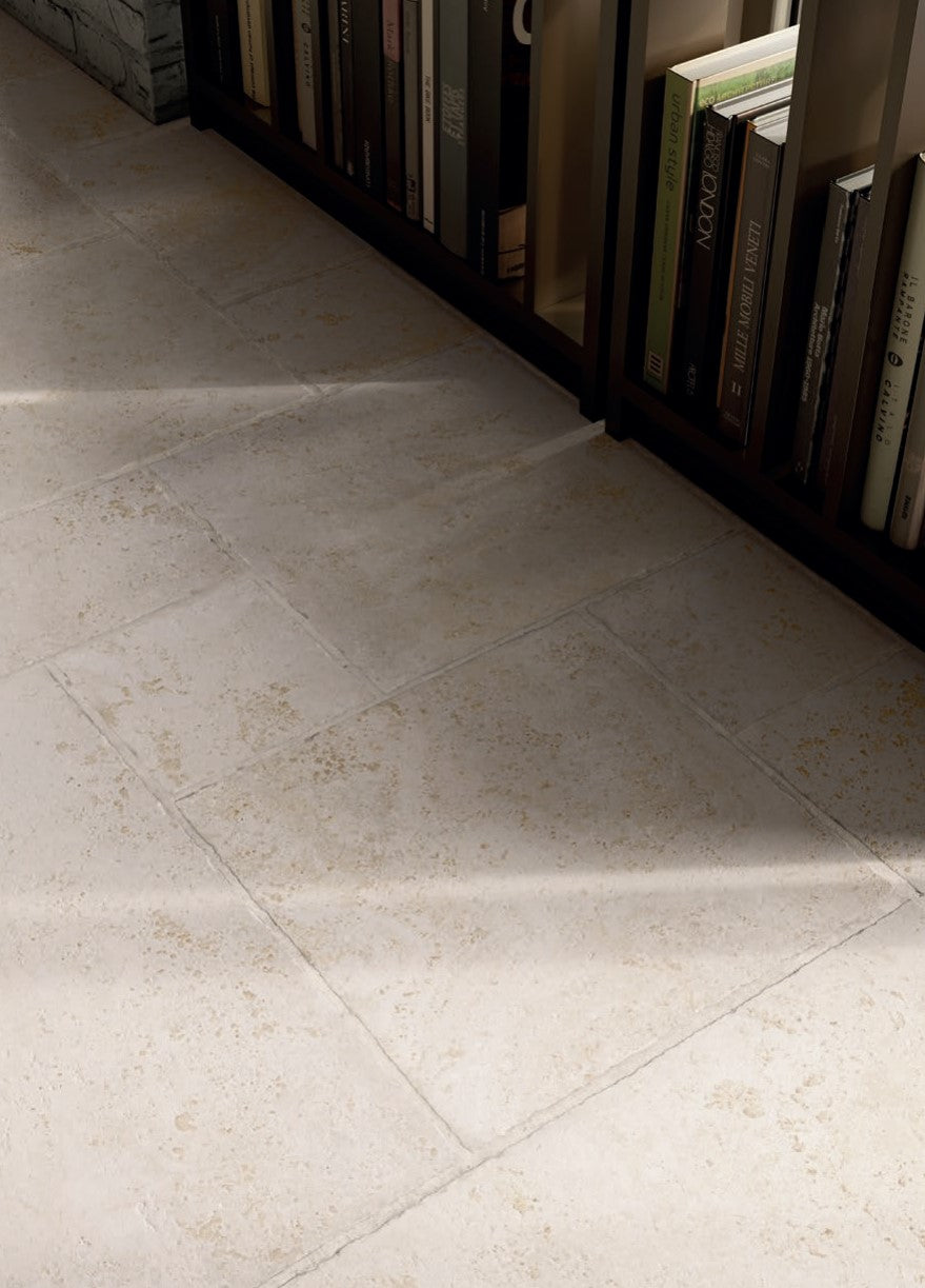 Tibur Bianco Safe Modulo French Pattern 400x600mm installed as a cream stone-look floor beside a dark wood bookshelf filled with books.