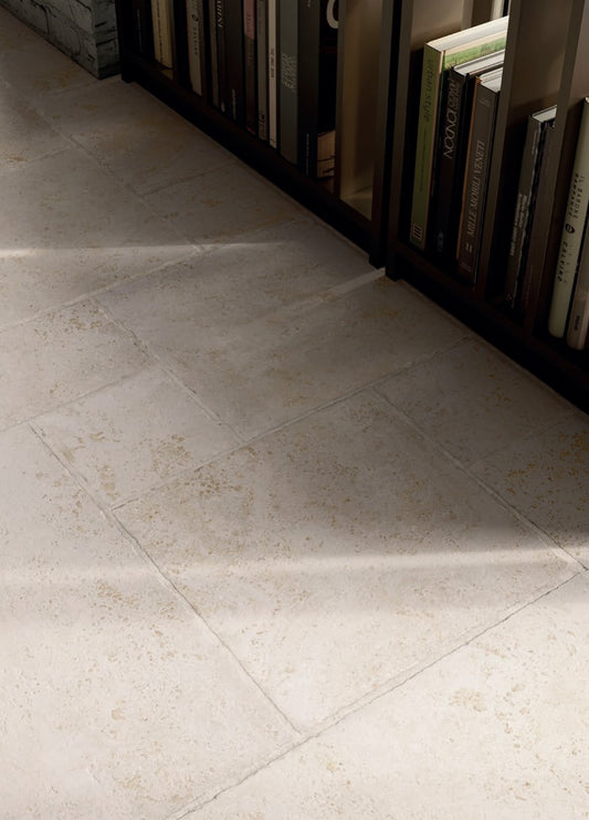 Tibur Bianco Safe Modulo French Pattern 400x600mm installed as a cream stone-look floor beside a dark wood bookshelf filled with books.