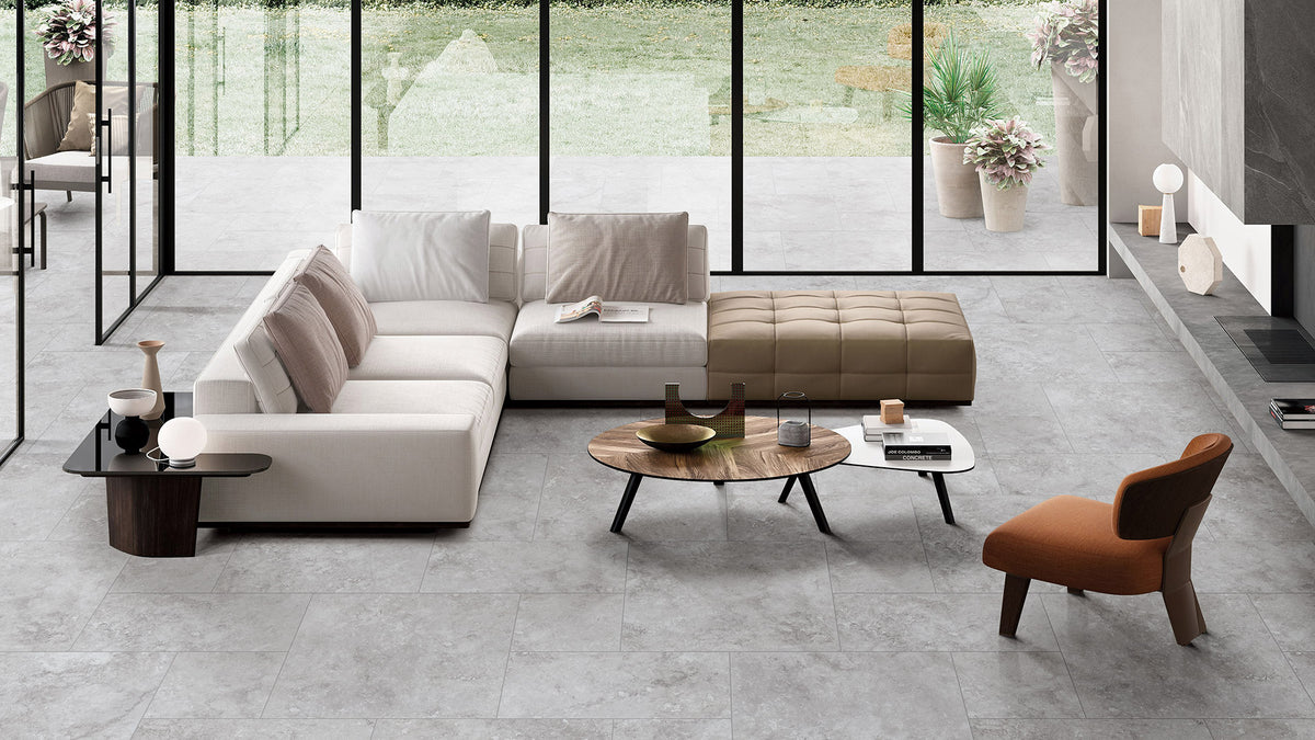 Timeless Silver Structured 600x600mm porcelain floor tiles installed in a modern open-plan living room with a sectional sofa and large glass windows.