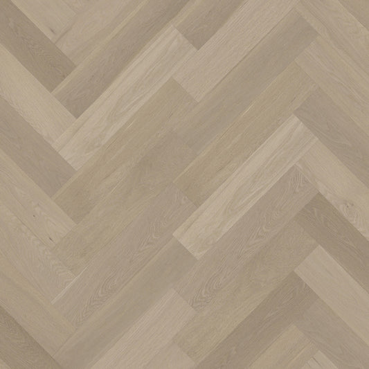 Close-up of Tinge Clay iDesign Herringbone Flooring 15/3mm showing a warm grey-beige oak wood surface laid in a classic diagonal herringbone pattern.