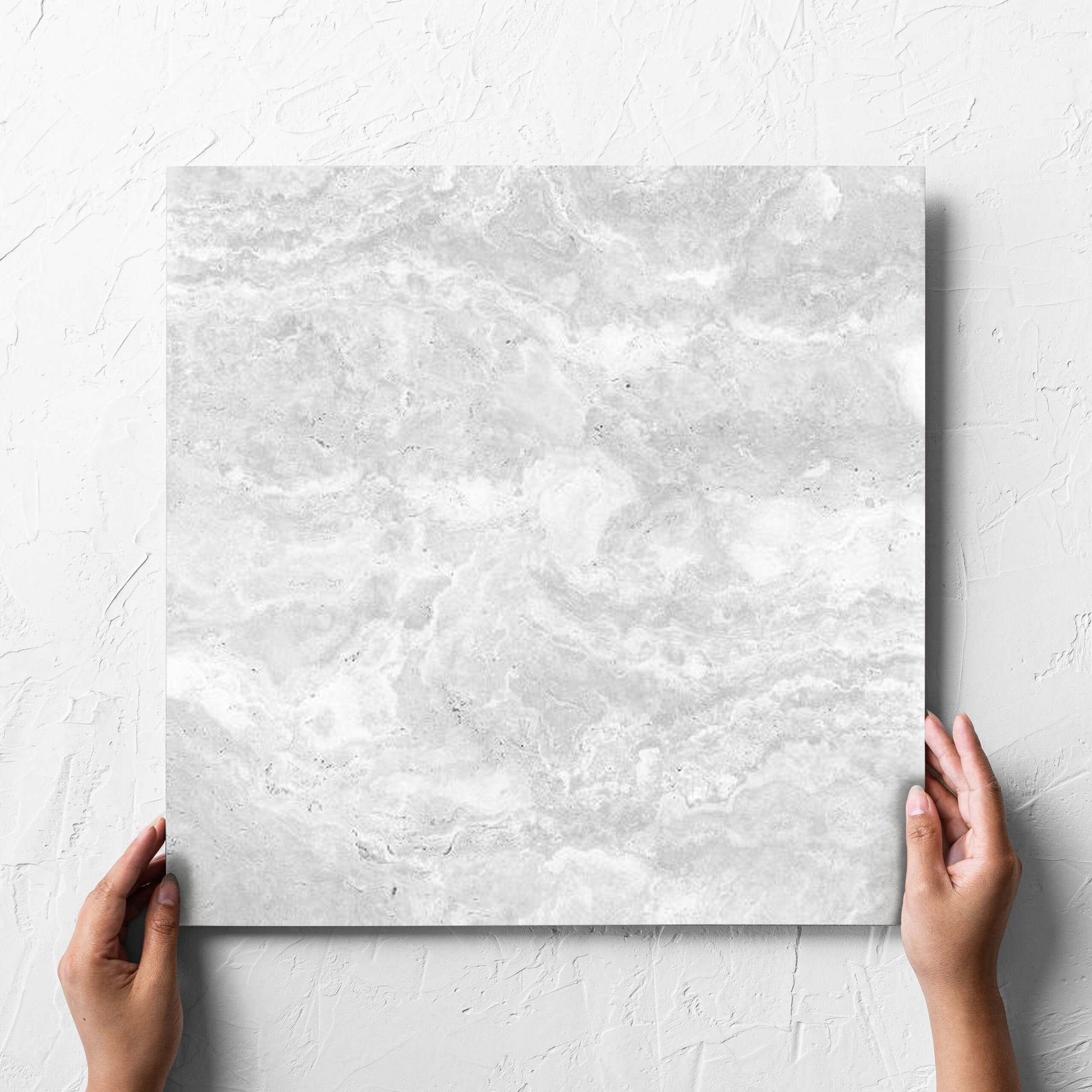 Hand holding a single Tivoli Silver Matt 450x450mm tile against a white rendered wall, showing the matt surface