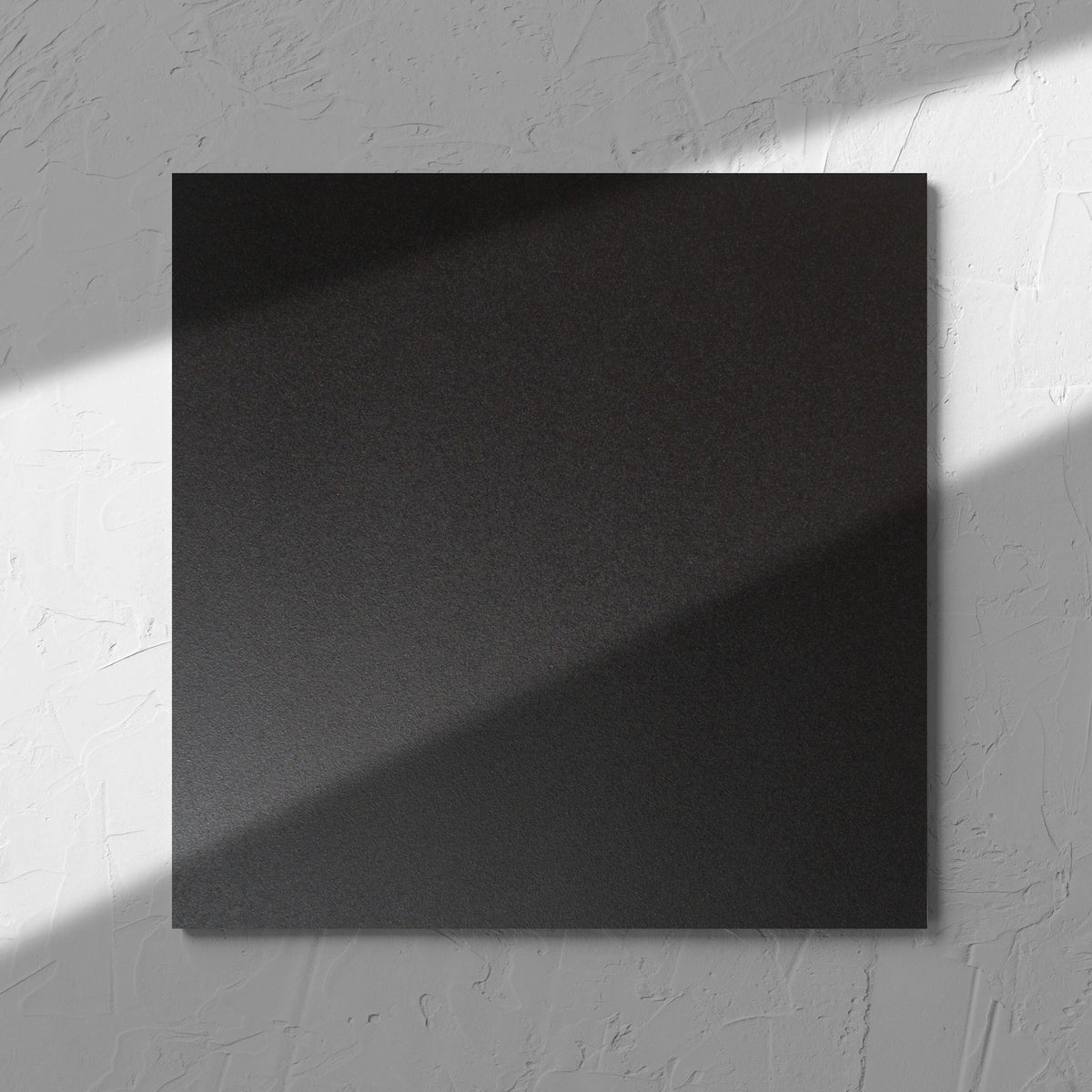 Unicolour Black Matt 300x300mm tile in soft natural window light, showing the black matt surface
