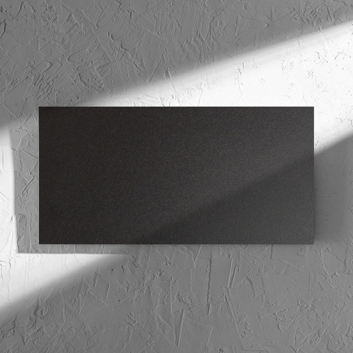 Unicolour Black Matt 300x600mm tile in soft natural window light, showing the black matt surface