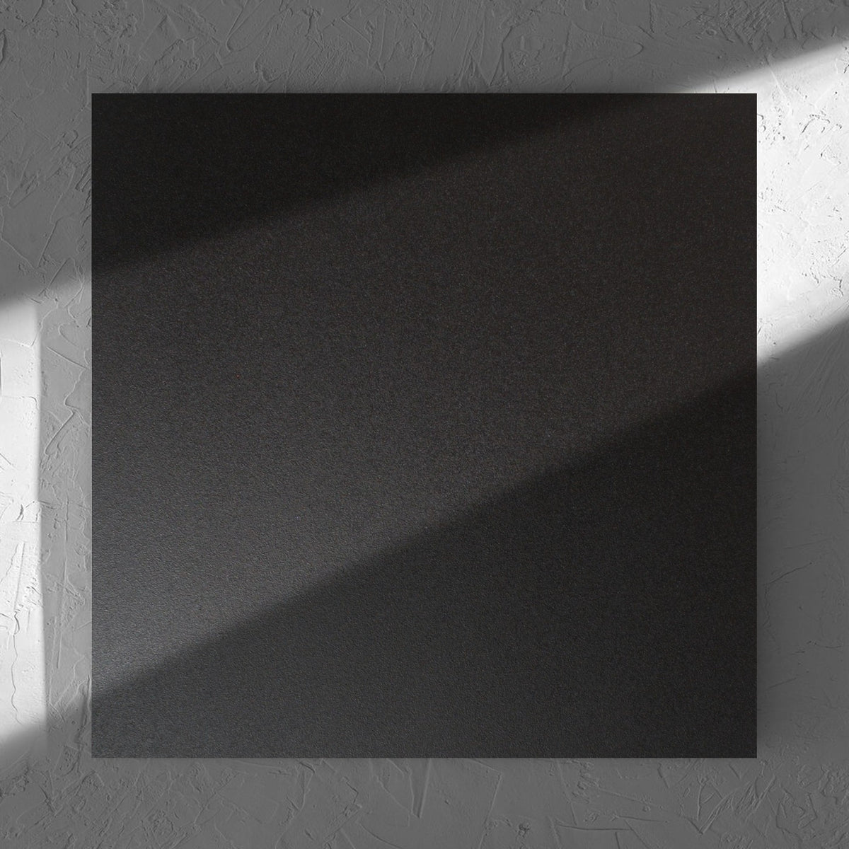 Unicolour Black Matt 600x600mm tile in soft natural window light, showing the black matt surface