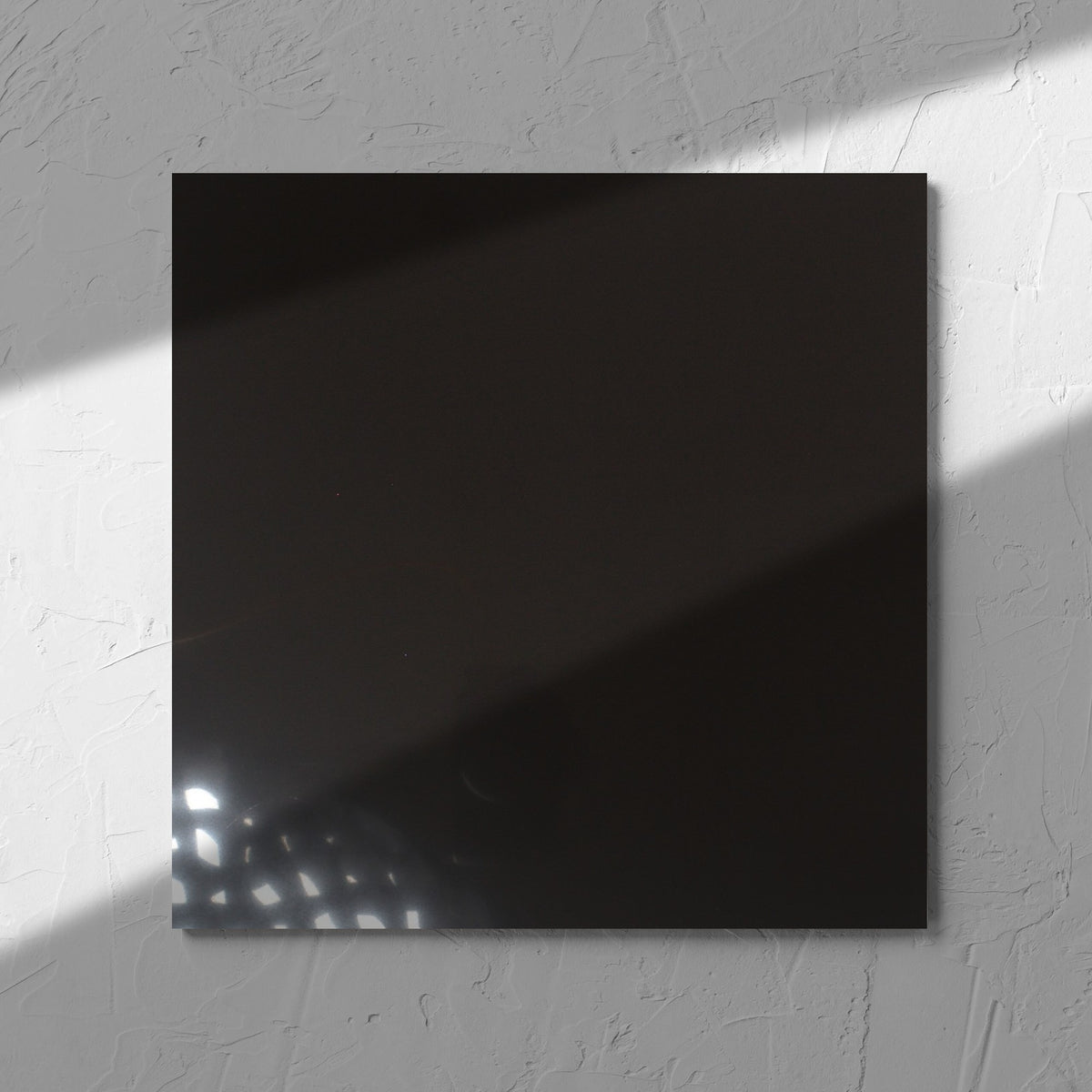 Unicolour Black Polished 300x300mm tile in soft natural window light, showing the black polished surface