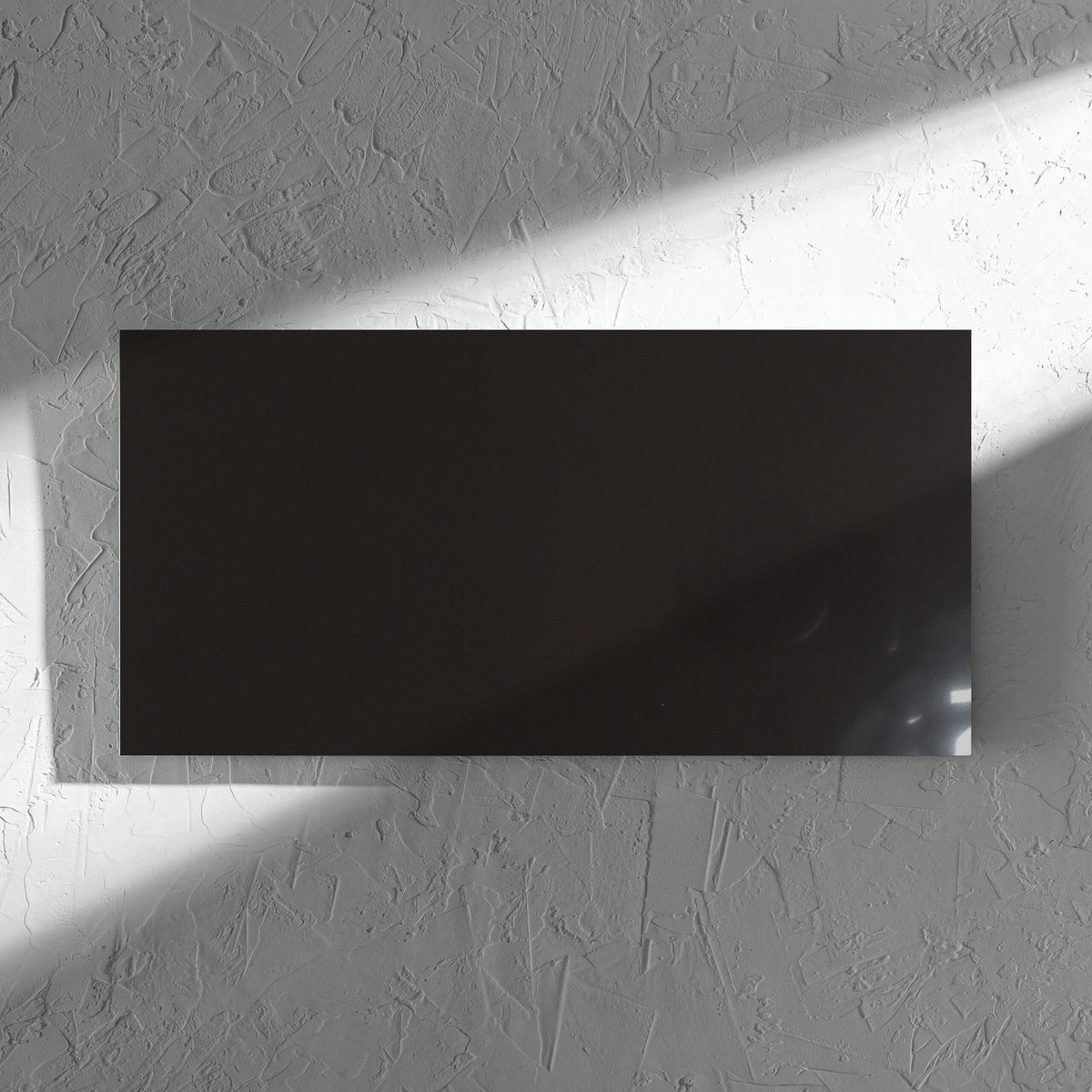 Unicolour Black Polished 300x600mm tile in soft natural window light, showing the black polished surface