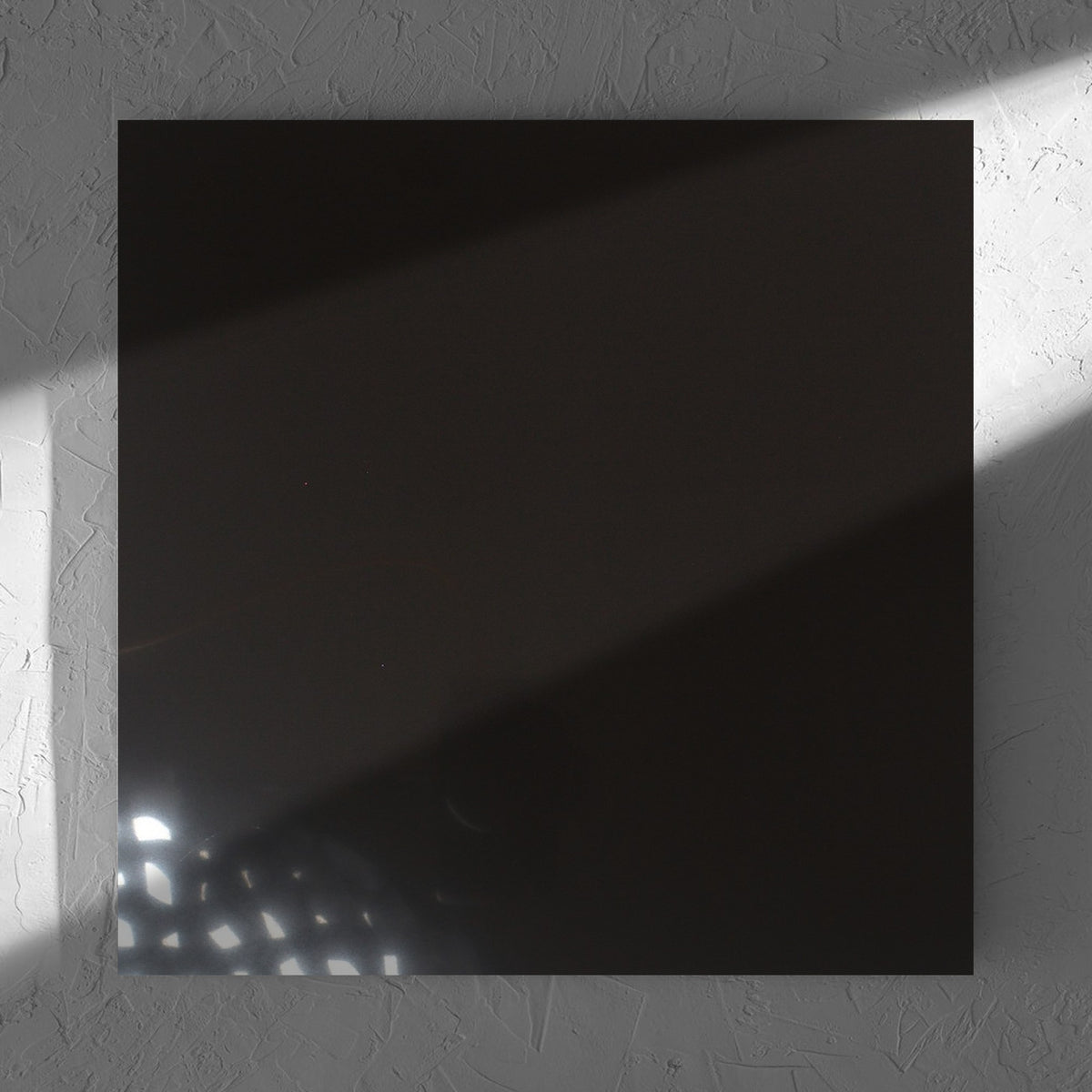 Unicolour Black Polished 600x600mm tile in soft natural window light, showing the black polished surface