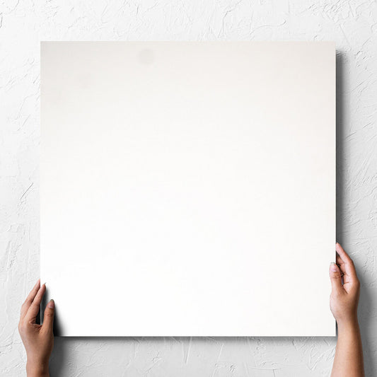 Hand holding a single Unicolour Super White Matt 600x600mm tile against a white rendered wall, showing the super white matt surface