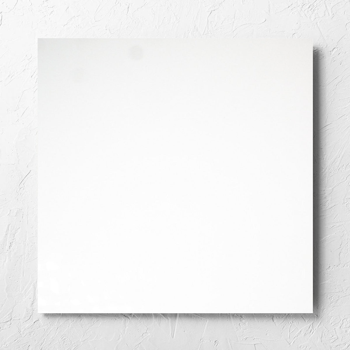 Unicolour White Polished 600x600mm tile laid flat on a white rendered wall, showing the white polished surface