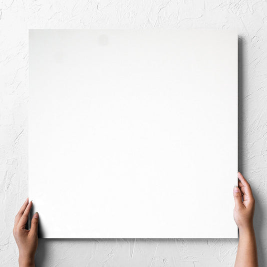 Hand holding a single Unicolour White Polished 600x600mm tile against a white rendered wall, showing the white polished surface