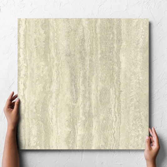 Hand holding a single Vatican Novona Vein Cut Travertine 600x600mm tile against a white rendered wall, showing the matt surface