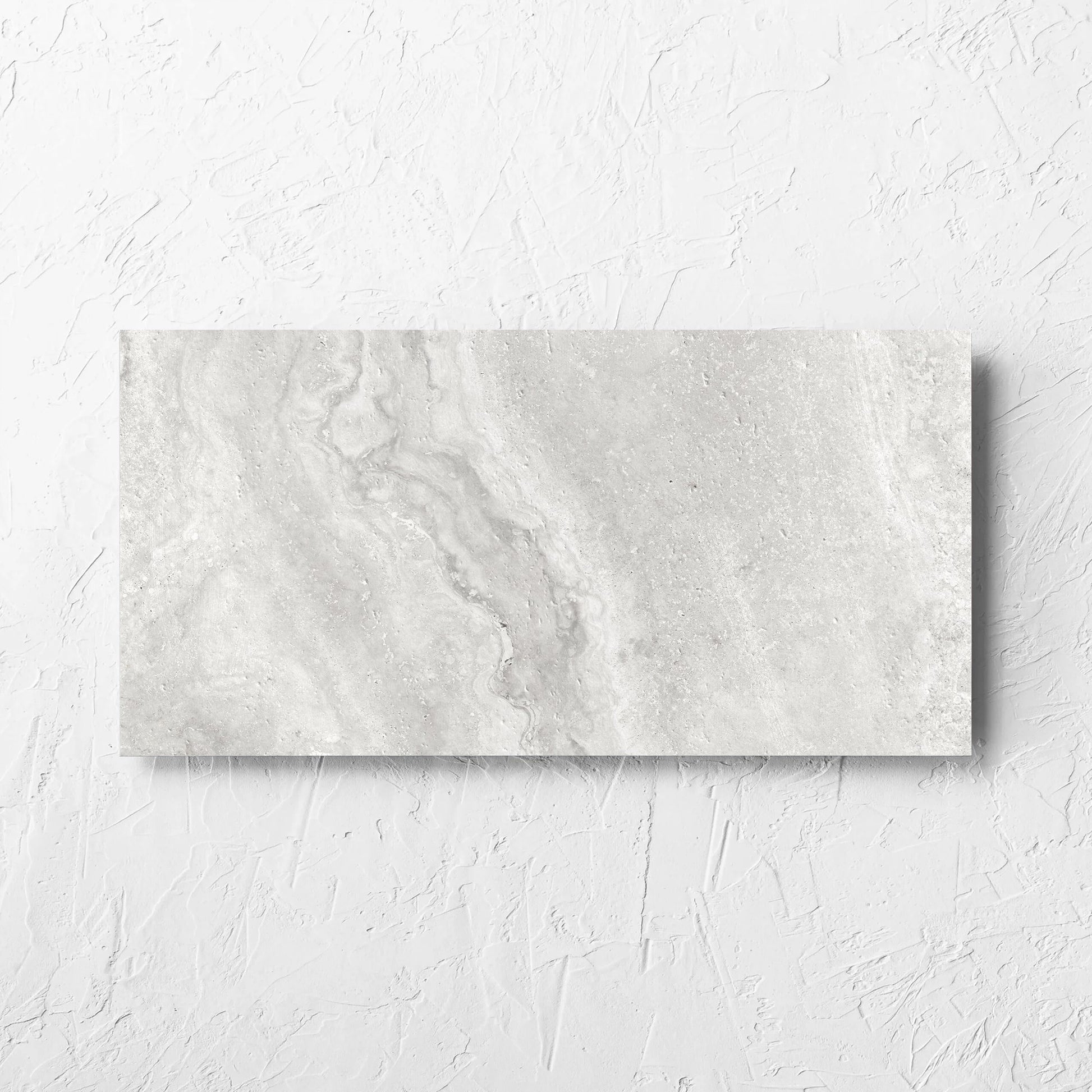 Vatican Silver Cross Cut Travertine 300x600mm tile laid flat on a white rendered wall, showing the matt surface