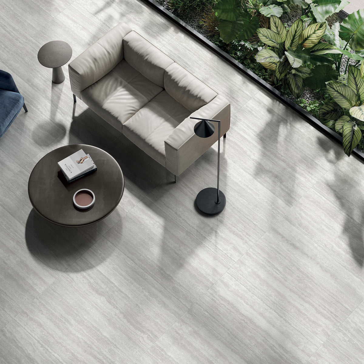 Vatican Silver Vein Cut Travertine Matt Linear 600x1200mm tiles covering a sunlit living room floor styled with a cream sofa, dark round coffee table, and floor lamp.